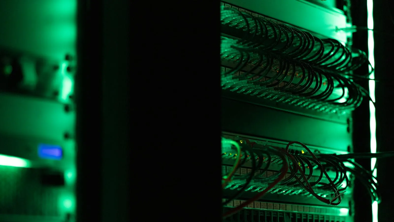 Rows of networking equipment in a dimly lit server room.