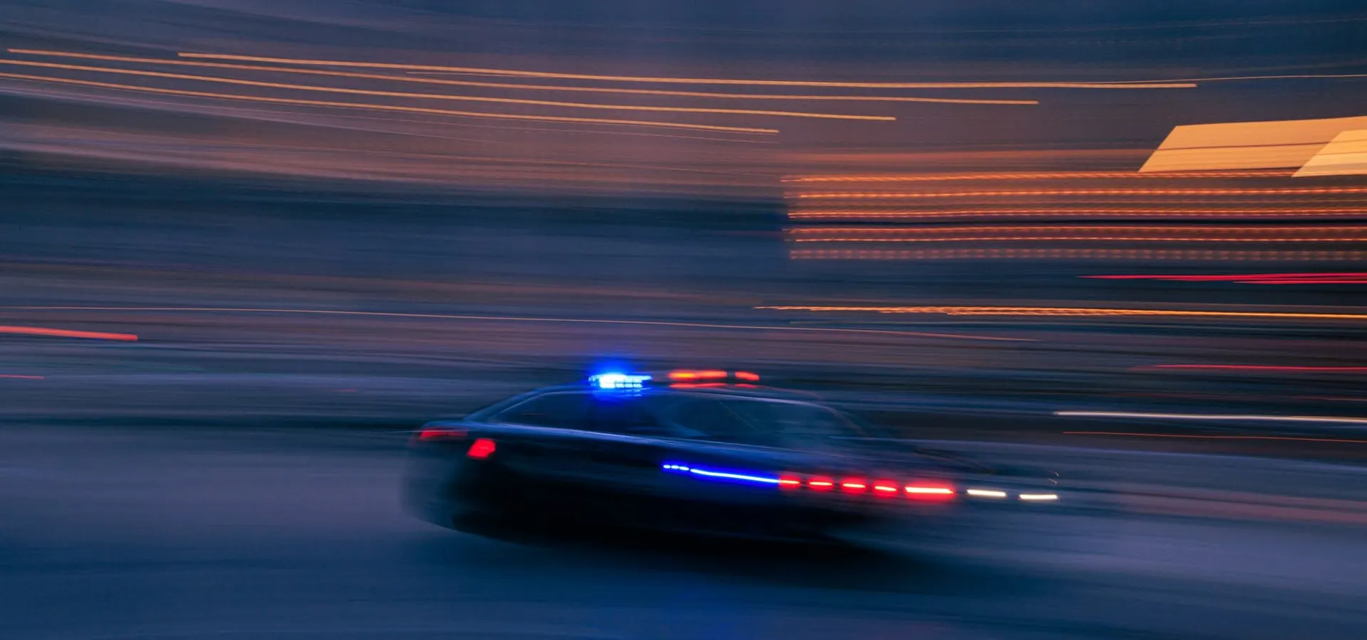 A patrol vehicle moving at speed at night with its emergency lights on.